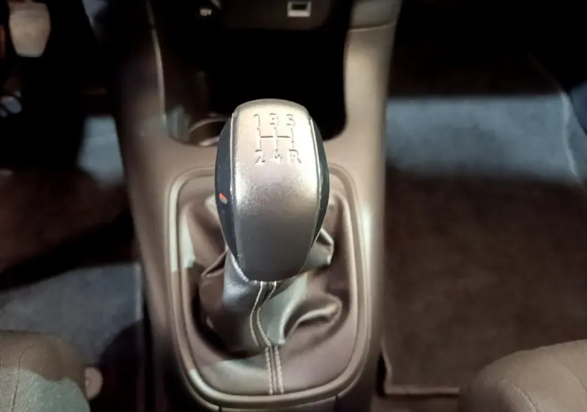 Le levier de vitesses manuel noir de la Citroën C3 blanche vu de dessus, entouré de l'habitacle sombre.