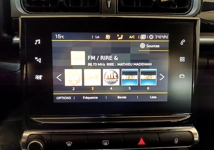 Écran tactile central de la CITROEN C3 blanche 2019 affichant les stations radio FM avec commandes climatisation en dessous.