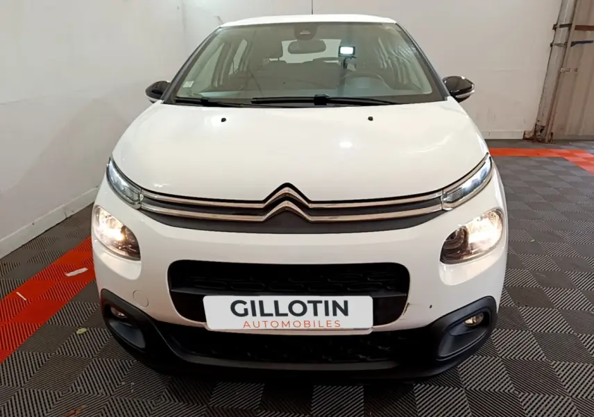 Vue frontale d'une Citroën C3 blanche 2019 avec phares allumés et calandre noire distinctive.