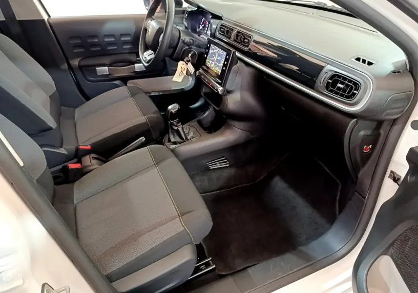 Intérieur avant droit d'une Citroën C3 blanche 2019, sièges gris, tableau de bord noir avec écran tactile central.