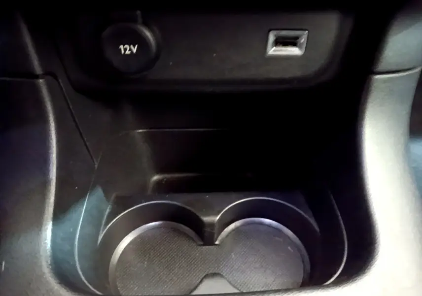 Gros plan sur la console centrale noire de la Citroën C3 2019, montrant porte-gobelets, prise 12V et port USB.