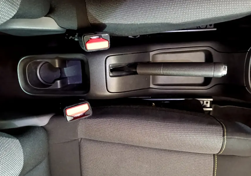 Vue plongeante sur la console centrale noire avec frein à main et ceintures de sécurité rouges d'une Citroën C3 2019.