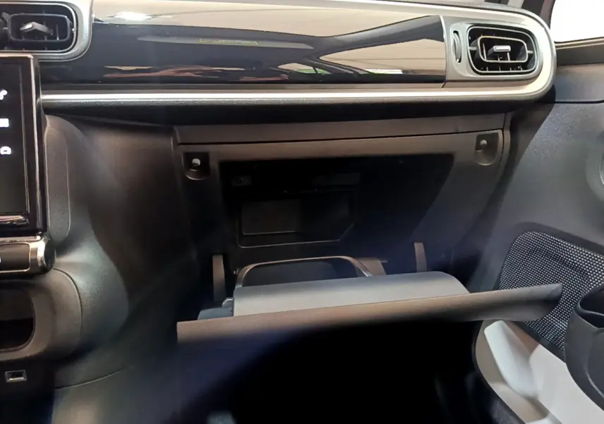 Intérieur de la Citroën C3 blanc, vue du tableau de bord côté passager avec boîte à gants ouverte et aérateurs rectangulaires.