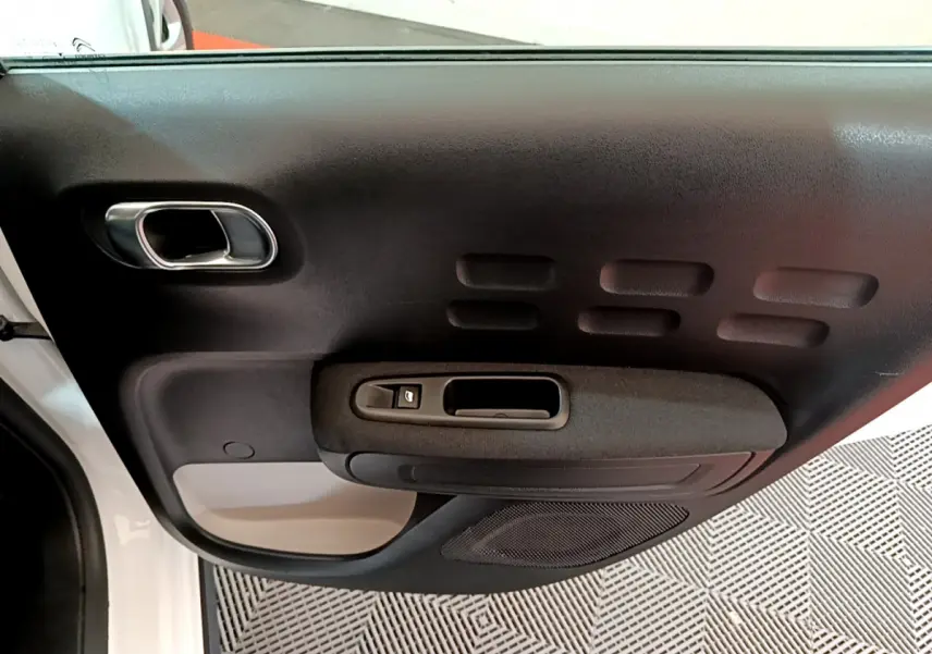 Gros plan sur la porte avant gauche blanche de la Citroën C3 2019 avec poignée et commande de vitre noire.
