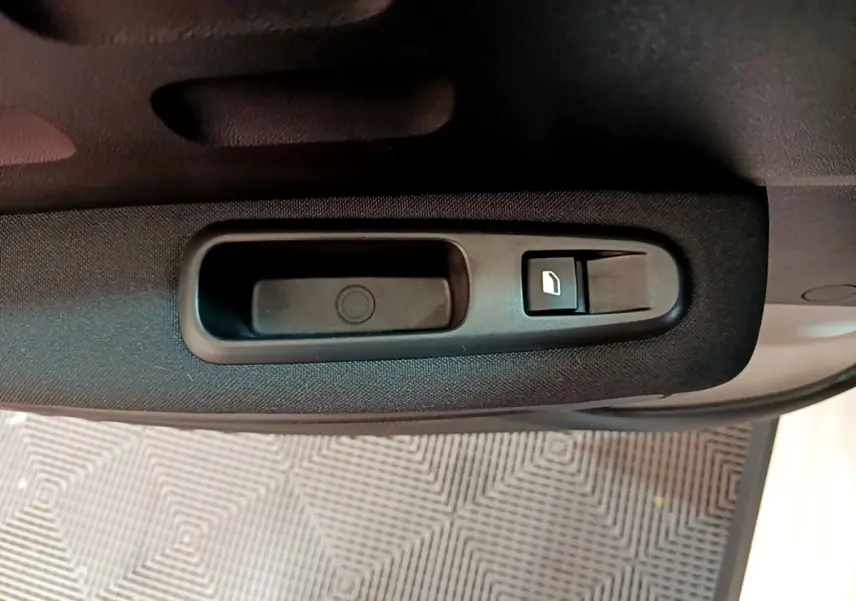Gros plan sur la commande de lève-vitre côté conducteur de la Citroën C3 blanche, intérieur tissu noir.