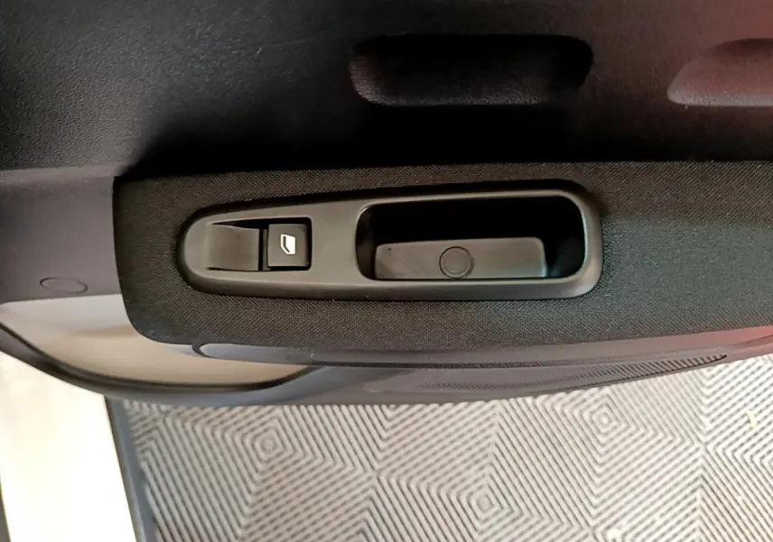 Gros plan sur la commande de lève-vitre côté gauche de la porte intérieure d'une Citroën C3 blanche de 2019.