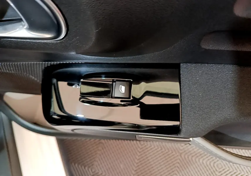 Gros plan sur la commande de lève-vitre noir brillant côté conducteur dans l'habitacle d'une Citroën C3 blanche 2019.