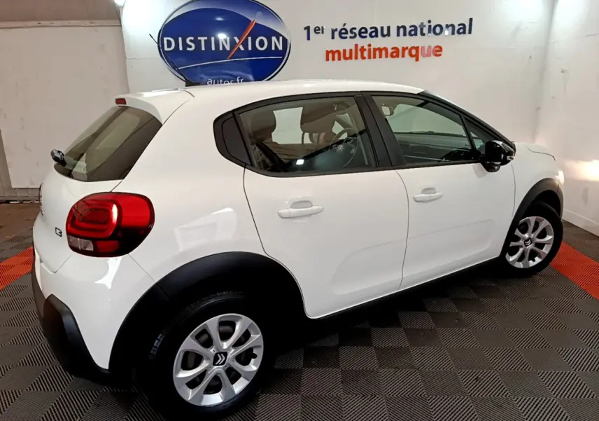 Citroën C3 blanche vue de côté droit arrière, avec jantes alliage et protections noires sur les passages de roues.