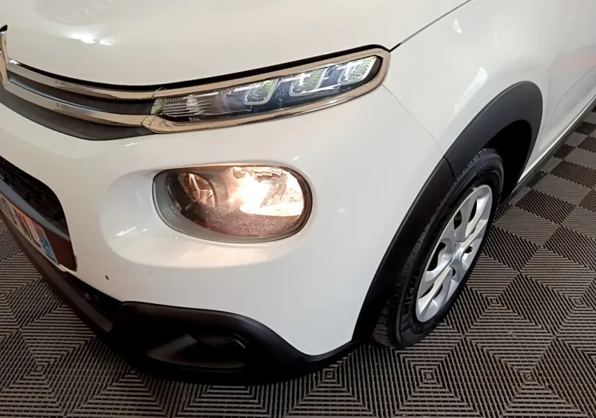Gros plan sur l'avant droit blanc du Citroën C3 2019 avec phares allumés et jante alu visible.
