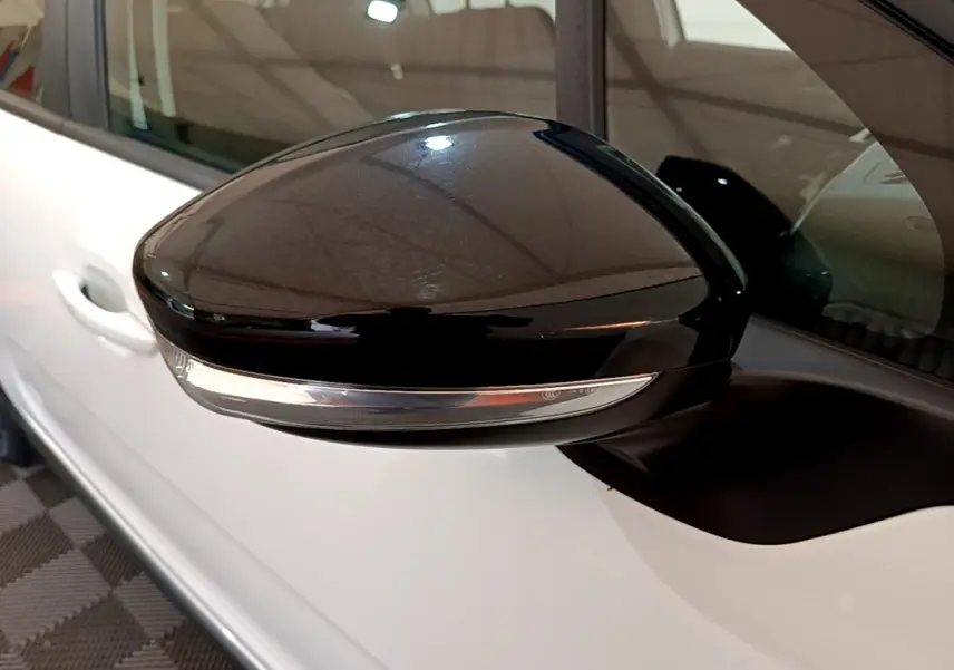 Rétroviseur noir côté gauche d'une Citroën C3 blanche, vue rapprochée sur la portière et la vitre.