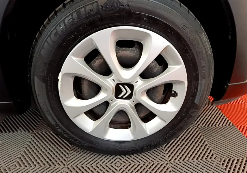 Gros plan sur la roue avant droite d'une Citroën C3 blanche, mettant en valeur la jante argentée au logo double chevron.