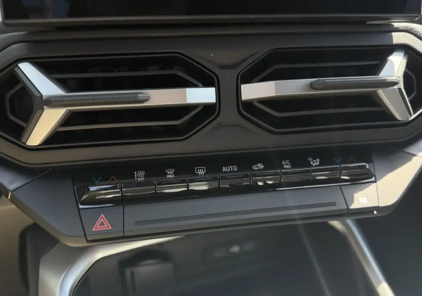 Gros plan sur la console centrale du Dacia Bigster 2026, montrant les aérateurs hexagonaux et les commandes de climatisation.