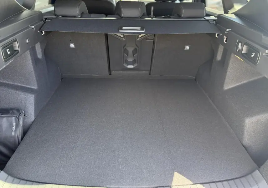 Coffre spacieux du Dacia Bigster Hybrid-G 150 4x4, vue arrière avec cache-bagages et banquette rabattable.