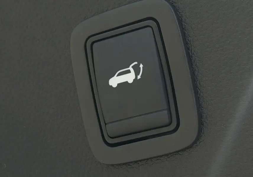 Bouton intérieur noir pour ouverture du hayon électrique sur Dacia Bigster Hybrid-G 150 bleu indigo.