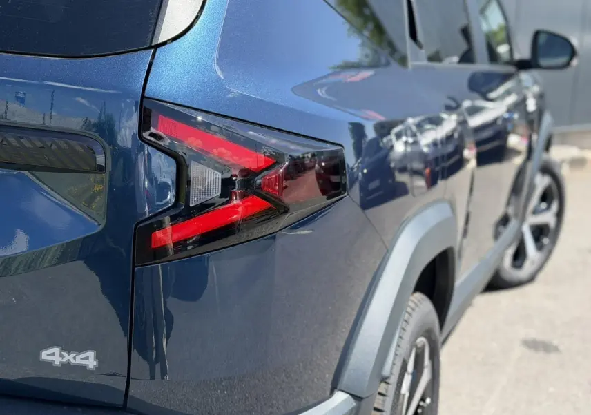 Vue 3/4 arrière droite du Dacia Bigster bleu indigo avec feux arrière en forme de flèche et logo 4x4 visible.