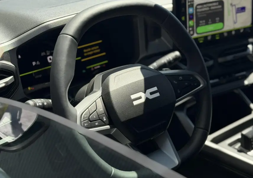 Gros plan sur le volant noir du Dacia Bigster 2026 avec tableau de bord numérique et écran tactile en arrière-plan.