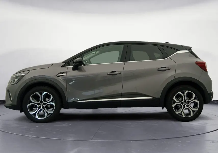 Vue de profil côté gauche du Renault Captur 1.3 Mild Hybrid 140 en gris Cassiopée avec toit noir et jantes alliage 18 pouces.