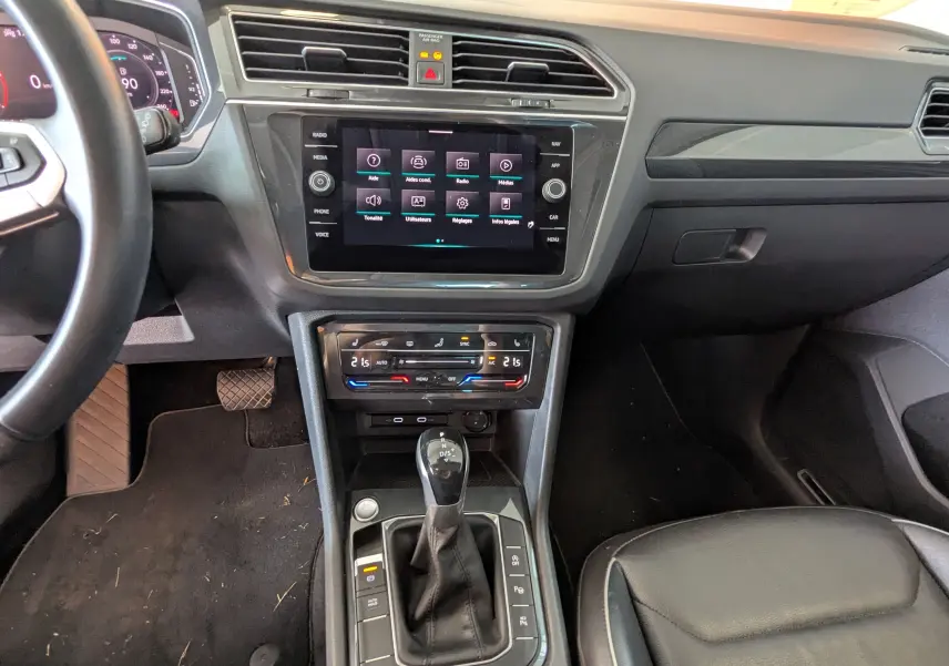 Vue intérieure centrée sur la console centrale et levier de vitesses du Volkswagen Tiguan noir avec écran tactile allumé.