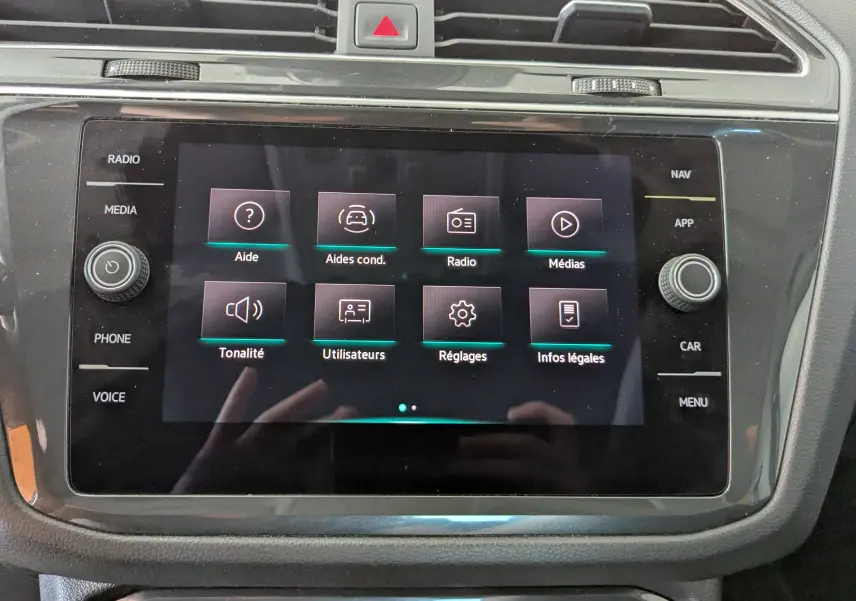 Écran tactile central du Volkswagen Tiguan 2.0 TDI 150ch noir, affichant le menu des aides à la conduite et réglages.