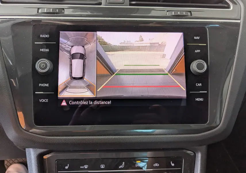 Écran central du Volkswagen Tiguan noir 2021 montrant la caméra de recul et l'alerte de distance au stationnement.