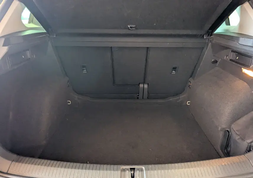 Coffre ouvert en vue arrière d'un Volkswagen Tiguan noir, montrant un espace de chargement vide et bien éclairé.