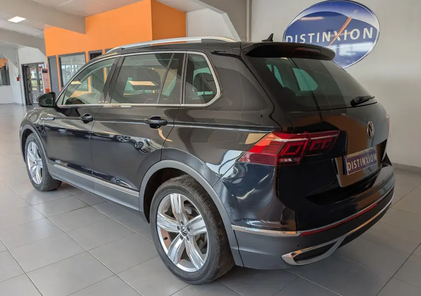 Vue 3/4 arrière droite d’un Volkswagen Tiguan noir 2021 dans un showroom avec jantes alliage et feux LED distinctifs.