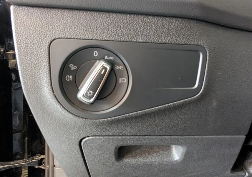 Gros plan sur le sélecteur de phares noir du Volkswagen Tiguan 2.0 TDI 150ch Elegance 2021, côté gauche intérieur.