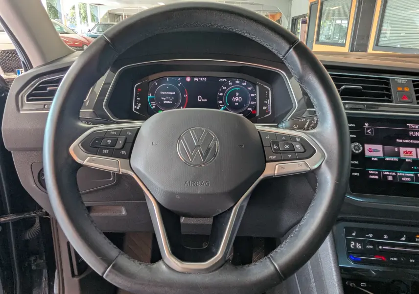 Vue intérieure centrée sur le volant noir du Volkswagen Tiguan 2021 avec tableau de bord numérique et console tactile visible.