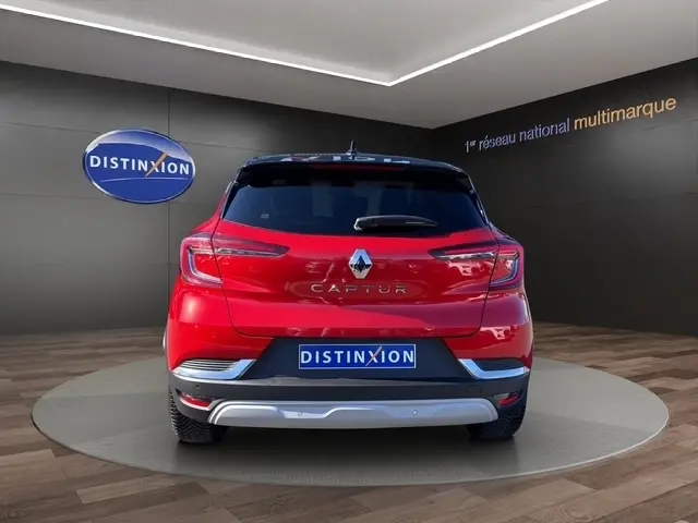 Vue arrière d'un Renault Captur rouge 2024 avec feux LED et logo distinctif sur fond intérieur showroom.