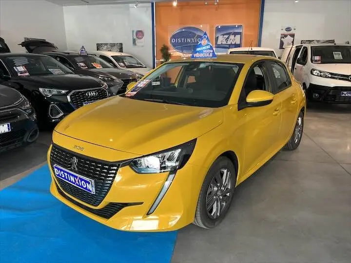Peugeot 208 jaune Faro Metal vue 3/4 avant droit dans un showroom avec logo Distinxion en arrière-plan.