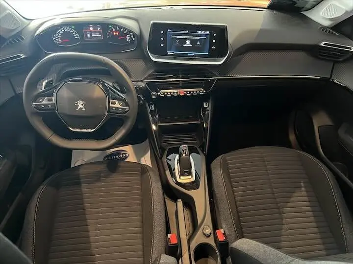 Vue intérieure frontale du poste de conduite de la Peugeot 208 1.2 essence, avec volant compact et écran tactile central.