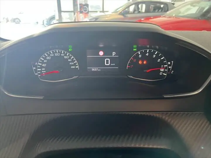 Tableau de bord numérique de Peugeot 208 essence 2021, affichant 0 km/h et 5637 km, avec voyants allumés.
