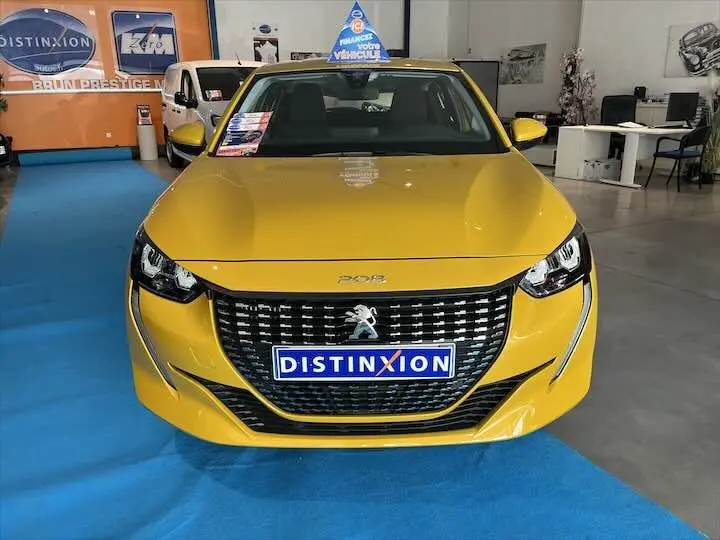 Peugeot 208 jaune Faro métal vue de face en intérieur, avec calandre noire et logo lion distinctif.