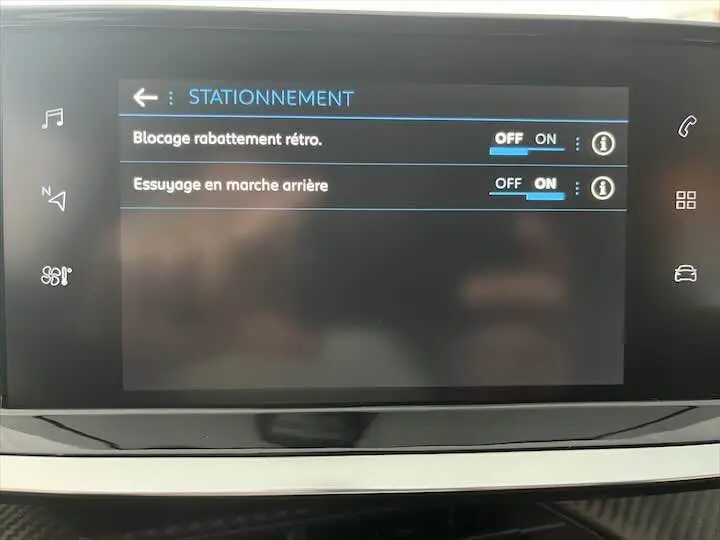 Écran tactile intérieur de la Peugeot 208 affichant les réglages d'aide au stationnement avec options activées.