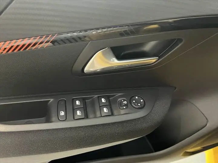 Gros plan sur la commande des vitres et la poignée intérieure côté gauche d'une Peugeot 208 jaune Faro Métal.