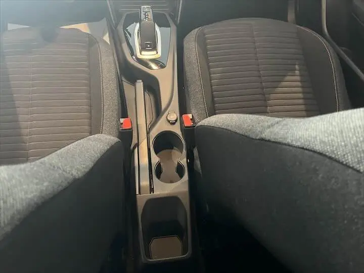 Vue rapprochée de la console centrale et des sièges avant noirs d'une Peugeot 208 1.2 essence, version Active Business.