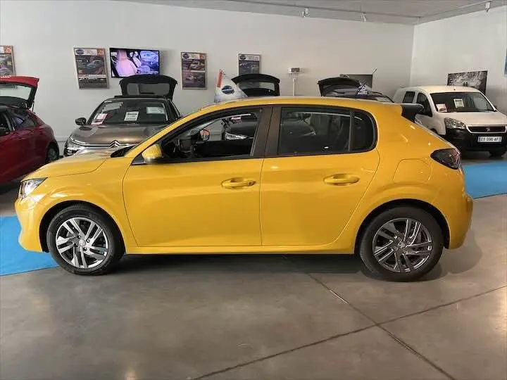 Profil côté gauche d'une Peugeot 208 jaune Faro Metal 2021 en intérieur, avec jantes alliage et poignées couleur carrosserie.
