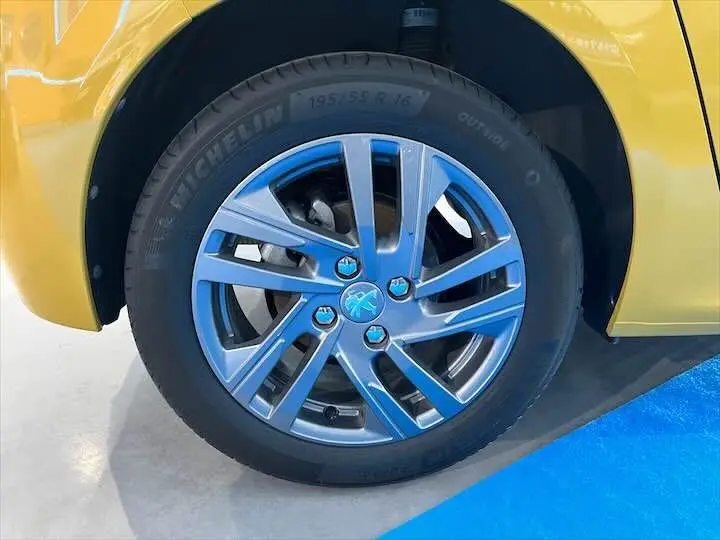 Gros plan sur la roue avant droite d'une Peugeot 208 jaune Faro Métal avec jante alliage et pneu Michelin.