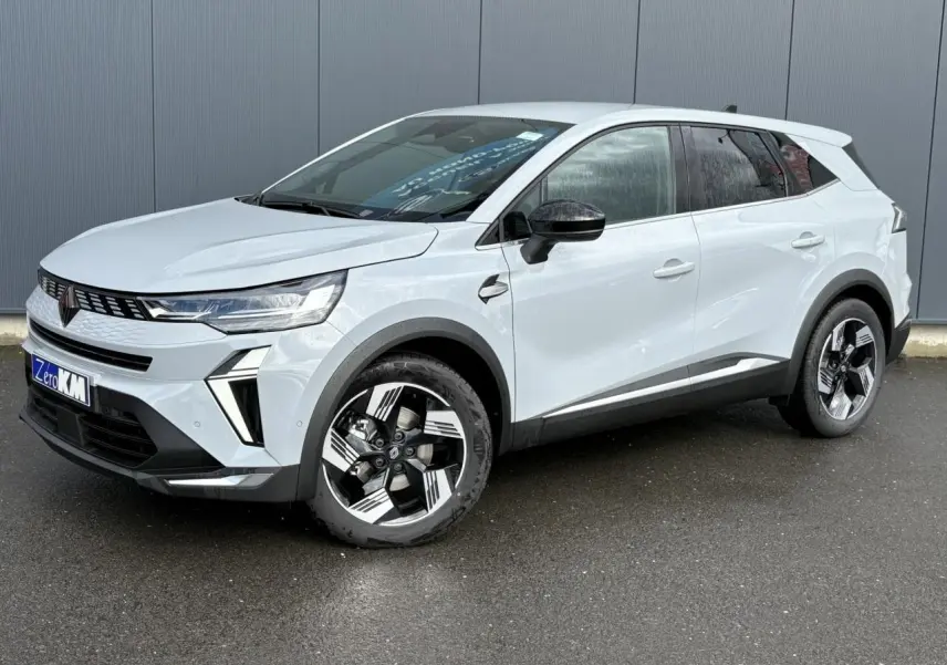 Renault Symbioz gris clair en 3/4 avant droit, avec jantes stylisées et calandre moderne sur fond urbain.