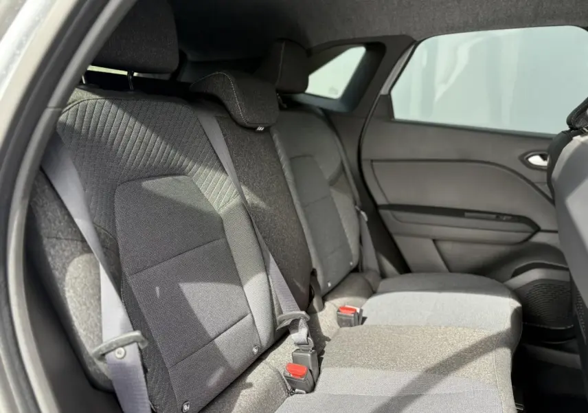 Vue latérale intérieure sur la banquette arrière grise du Renault Symbioz 2025 avec ceintures et appuie-têtes réglables.