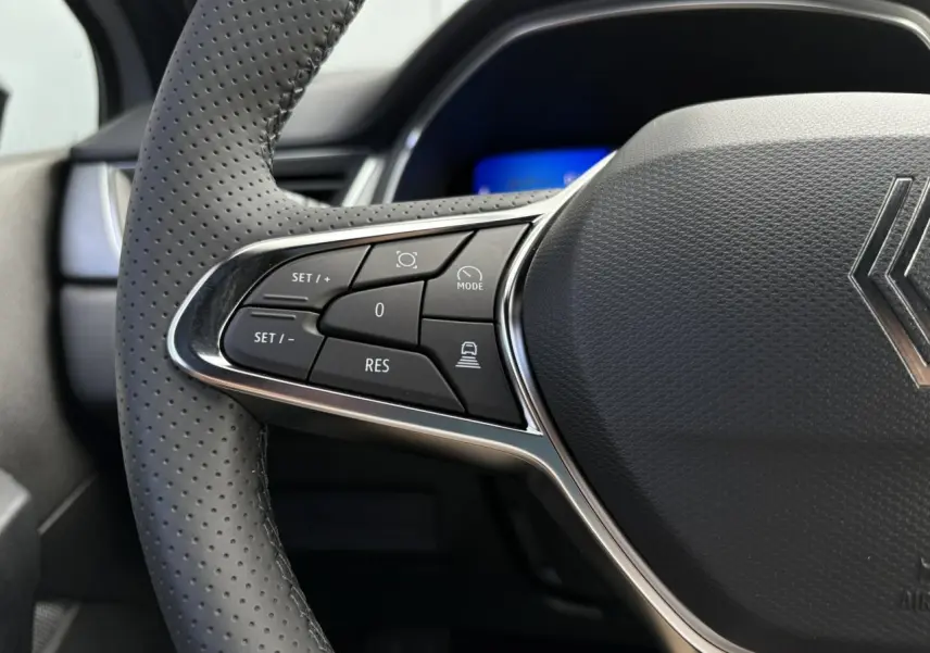 Gros plan sur le volant en cuir perforé gris du Renault Symbioz 2025, avec commandes multifonctions côté gauche.