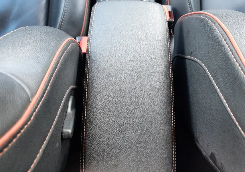 Accoudoir central en cuir noir avec surpiqûres orange entre les sièges avant du Renault Captur blanc toit noir 2020.