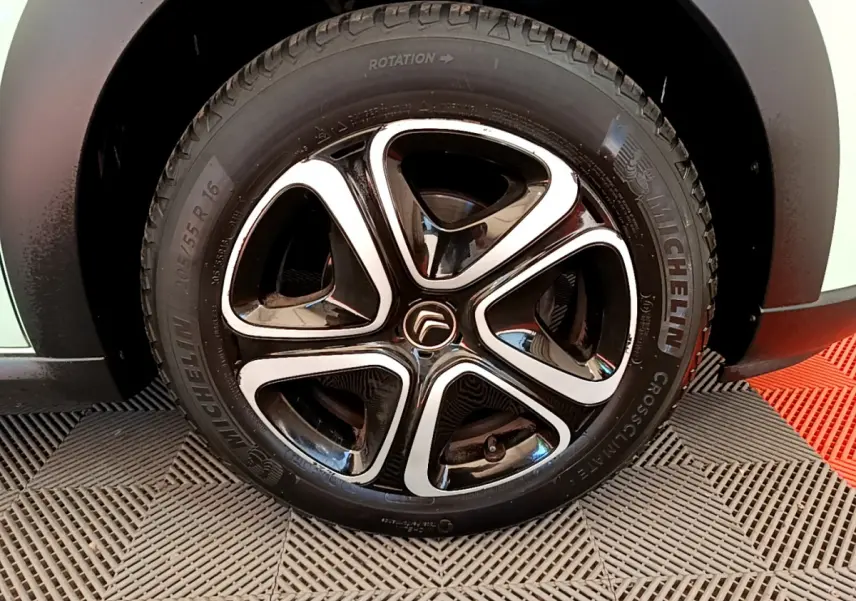 Gros plan sur la roue avant droite d'une Citroën C3 verte, jante noire et argent avec pneu Michelin.