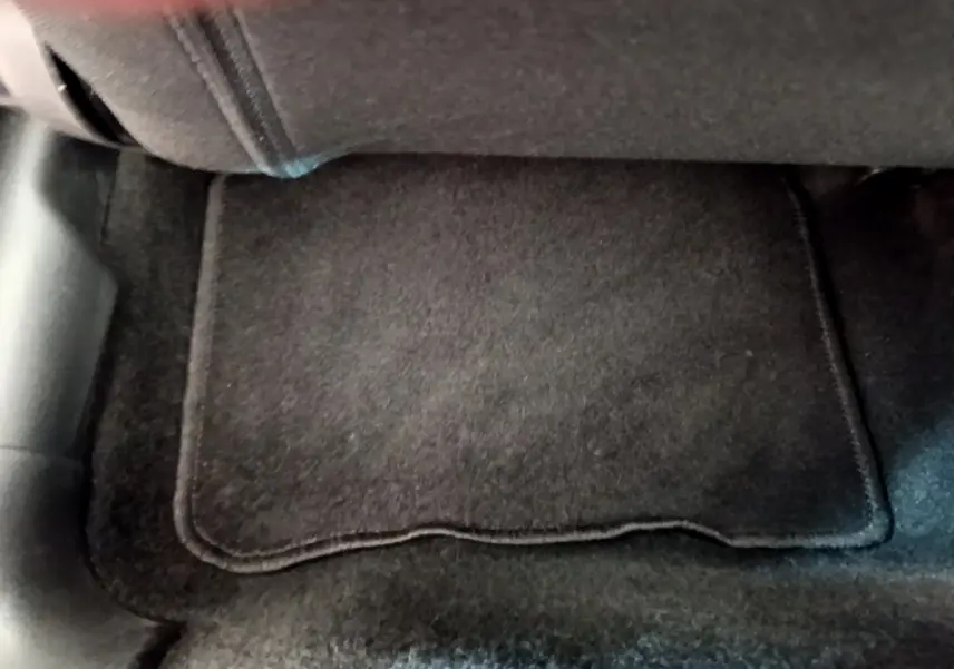 Vue rapprochée du tapis de sol noir sous le siège arrière d'une Citroën C3 vert 2019.