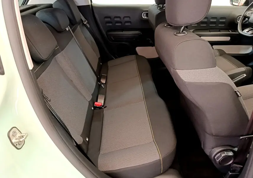 Vue intérieure côté gauche montrant la banquette arrière et les sièges avant noirs de la Citroën C3 vert 2019.