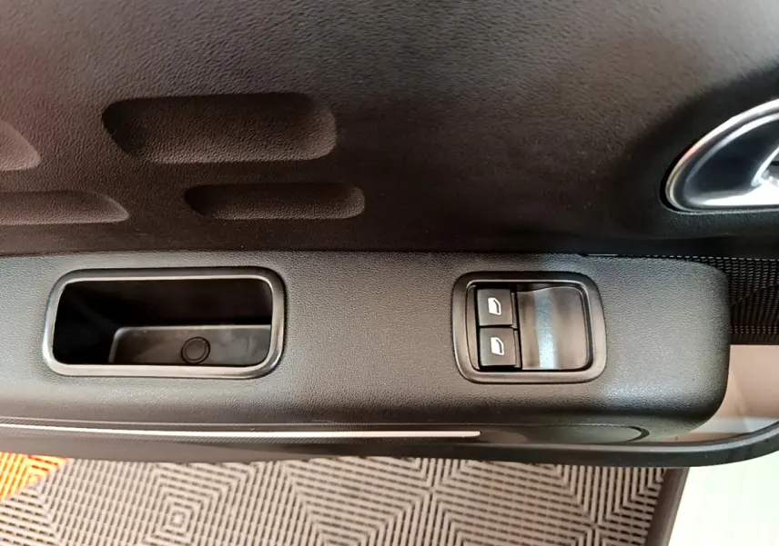 Gros plan sur la commande des vitres électriques côté gauche de la porte intérieure d'une Citroën C3 vert 2019.