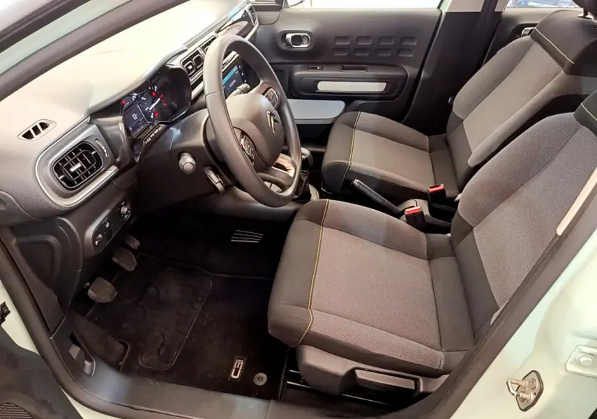 Intérieur avant de la Citroën C3 vert clair, sièges gris avec surpiqûres jaunes et tableau de bord moderne tactile.