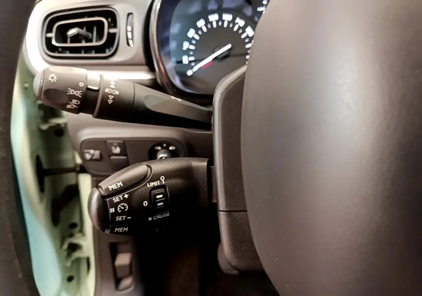 Gros plan sur le volant et commandes au volant côté gauche d'une Citroën C3 vert 2019, avec tableau de bord visible.
