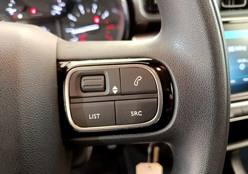Gros plan sur les commandes gauche du volant noir de la Citroën C3 PureTech 82 S&S BVM Graphic 2019.