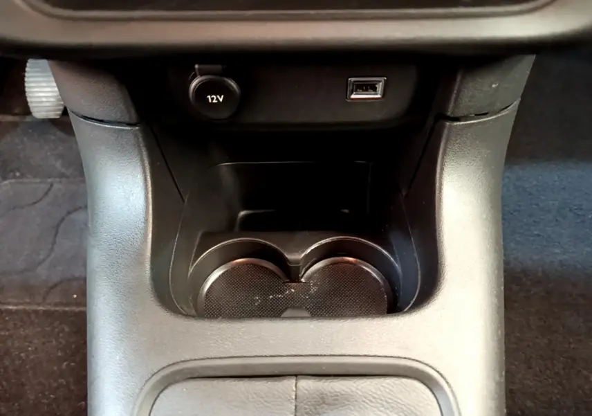Gros plan sur la console centrale noire avec prise 12V, port USB et porte-gobelets de la Citroën C3 2019.